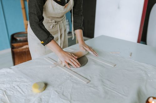 Free Woman shaping clay with a rolling pin in a pottery workshop, focusing on art and craft skills. Stock Photo