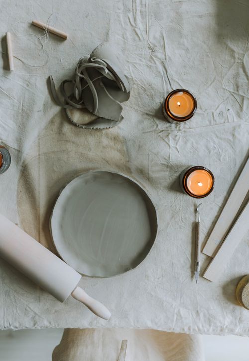 Free A serene pottery setup with candles on a workbench, creating a creative and calm atmosphere. Stock Photo