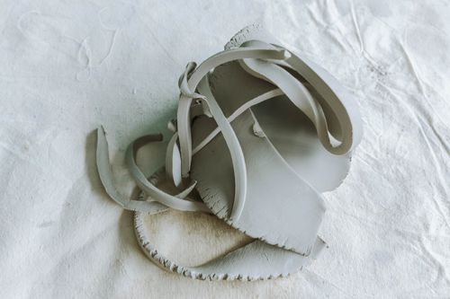 Free Minimalist close-up of abstract clay sculpture with a serene white background. Stock Photo
