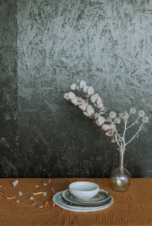 Ceramic Flatware Beside Glass Vase with Dried Flowers