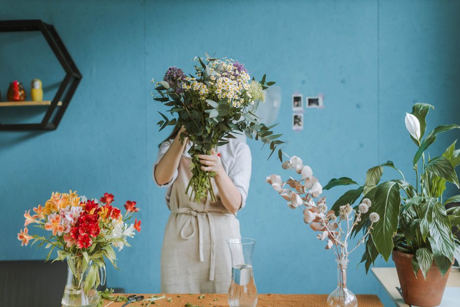 A florist delicately arranges a vibrant floral bouquet in a modern studio setting.