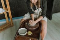 Woman in White Long Sleeve Shirt and Gray Vest Sitting on Brown Wooden Seat