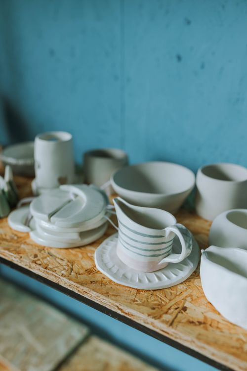 Free Elegant white ceramic dinnerware set on a wooden shelf against a blue wall. Stock Photo