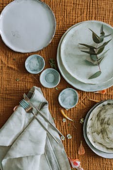 乡村餐桌设置的顶视图，带有陶瓷板、餐具和新鲜绿色植物