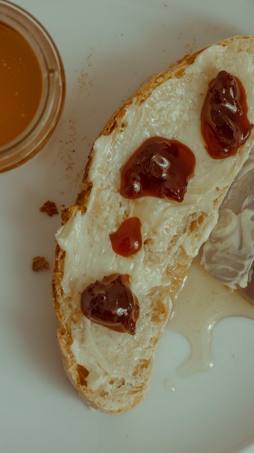 Free Vertical shot of buttered bread with jam alongside a cup of tea, perfect for breakfast scenes. Stock Photo