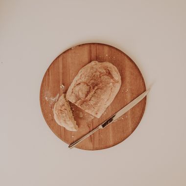 Rustic loaf of bread on a round wooden board — photo by Sarah on Pexels