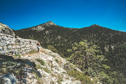 A Person Walking on a Hill Under Blue Sky