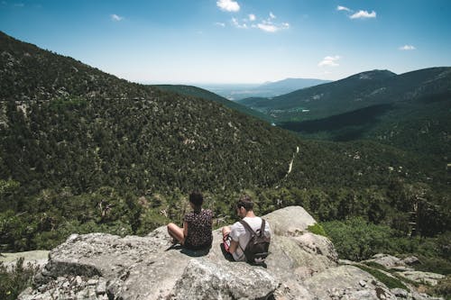 Back View of Couple Sitting on Rocks Overlooking Mountains