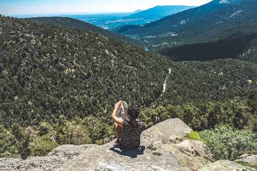 Free A Person Sitting on Rock on the Top of a Hill while Looking a Map Stock Photo