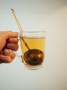 Transparent mug with tea infuser in hand of anonymous person on light background