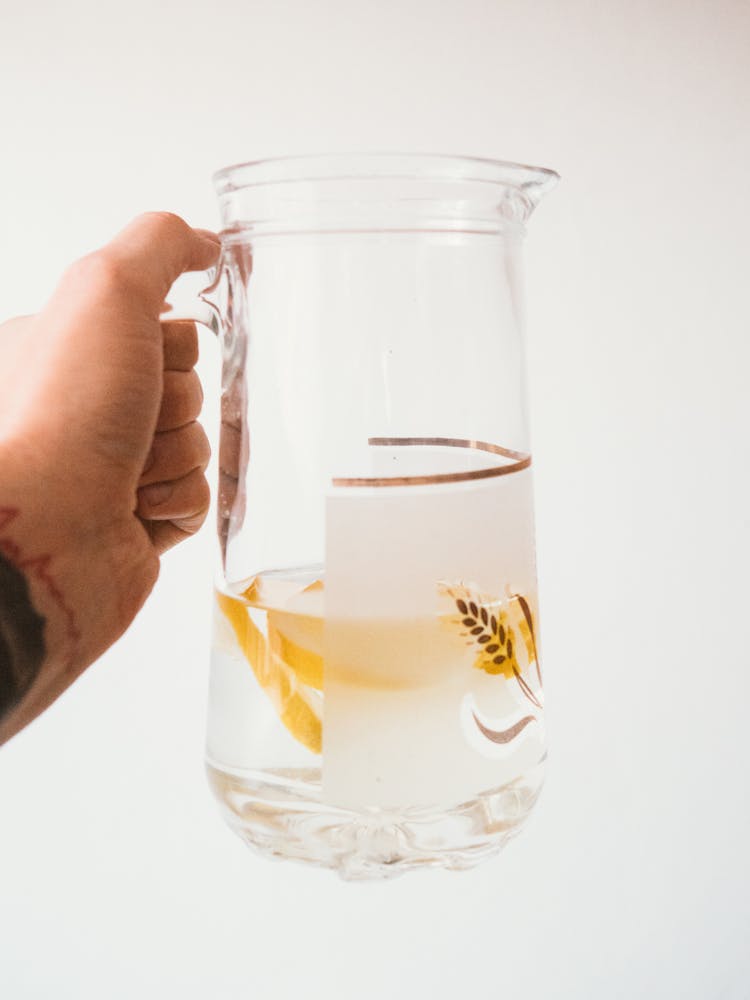 Hand Holding Pitcher Of Water On White Background