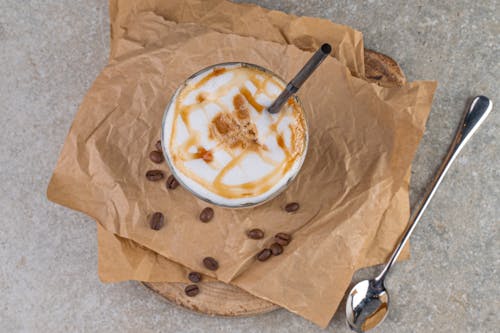 Gratis lagerfoto af kaffebønner, karamel, kop og underkop