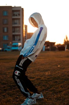 A fashionable teenager poses in a hoodie outdoors at sunset, creating a trendy and vibrant scene.