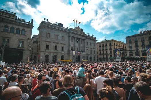 A lively gathering in a historic plaza in Barcelona, showcasing vibrant urban life under a bright sky.