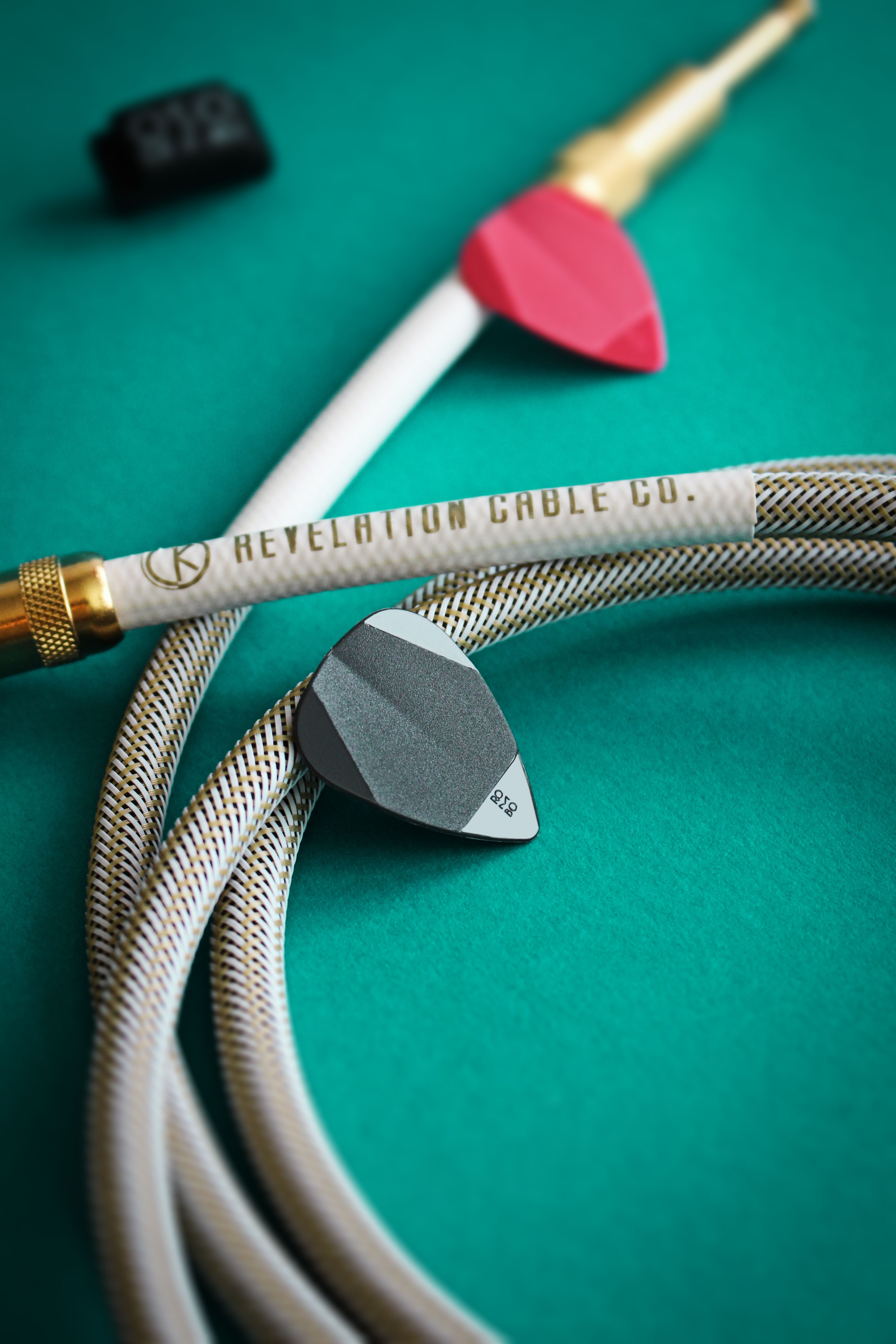 Detailed photo of guitar picks and cables on a textured green surface for music enthusiasts.