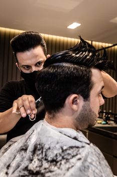 Barber styling a client's hair with precision in a modern barbershop.