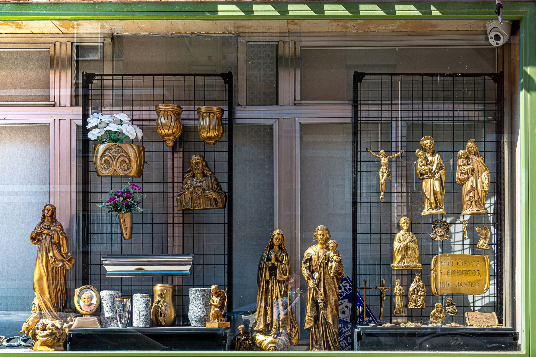 A detailed window display featuring religious figurines and symbols, captured in daylight.