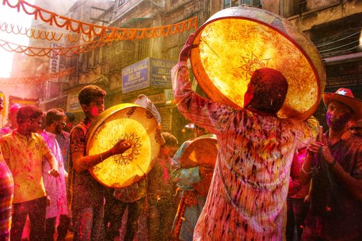 Colorful Holi festival celebration with drums and crowd in Kolkata, India.
