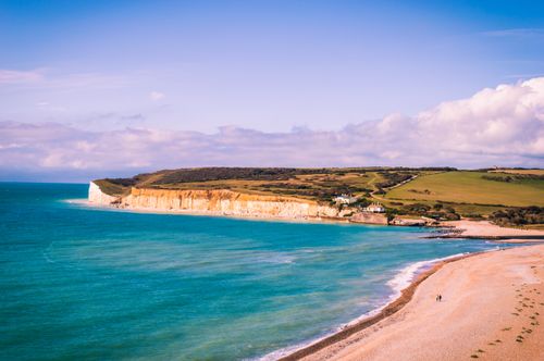Free A breathtaking aerial view of Eastbourne's coastline, showcasing cliffs, turquoise waters, and sandy beach under a clear summer sky. Stock Photo