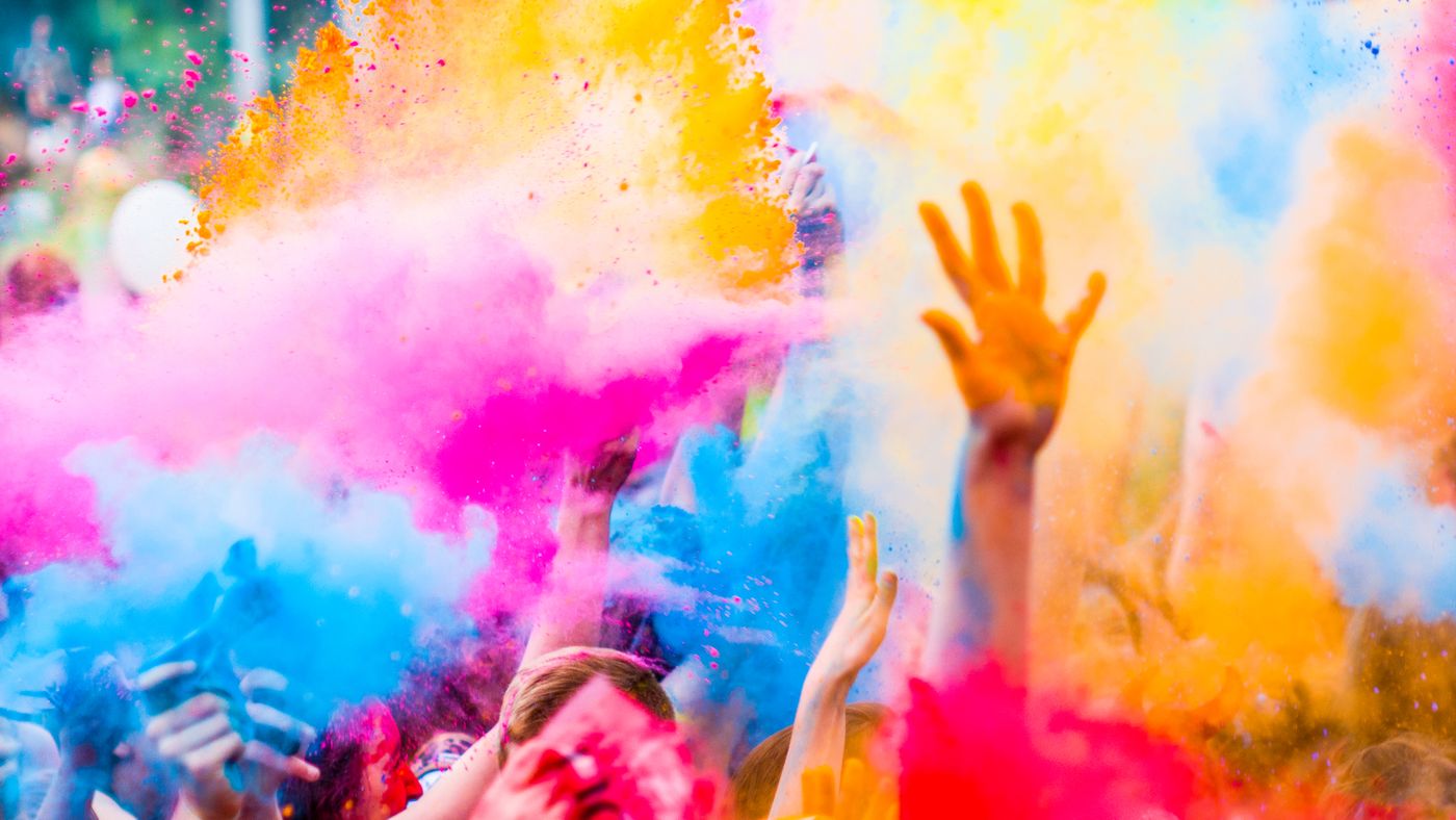 Cheerful crowd celebrating with vibrant colorful powder thrown in the air