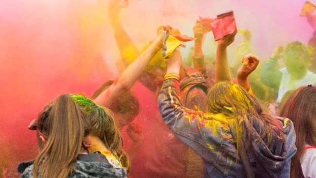People enjoying a lively festival with colorful powder in the air, symbolizing joy and unity.