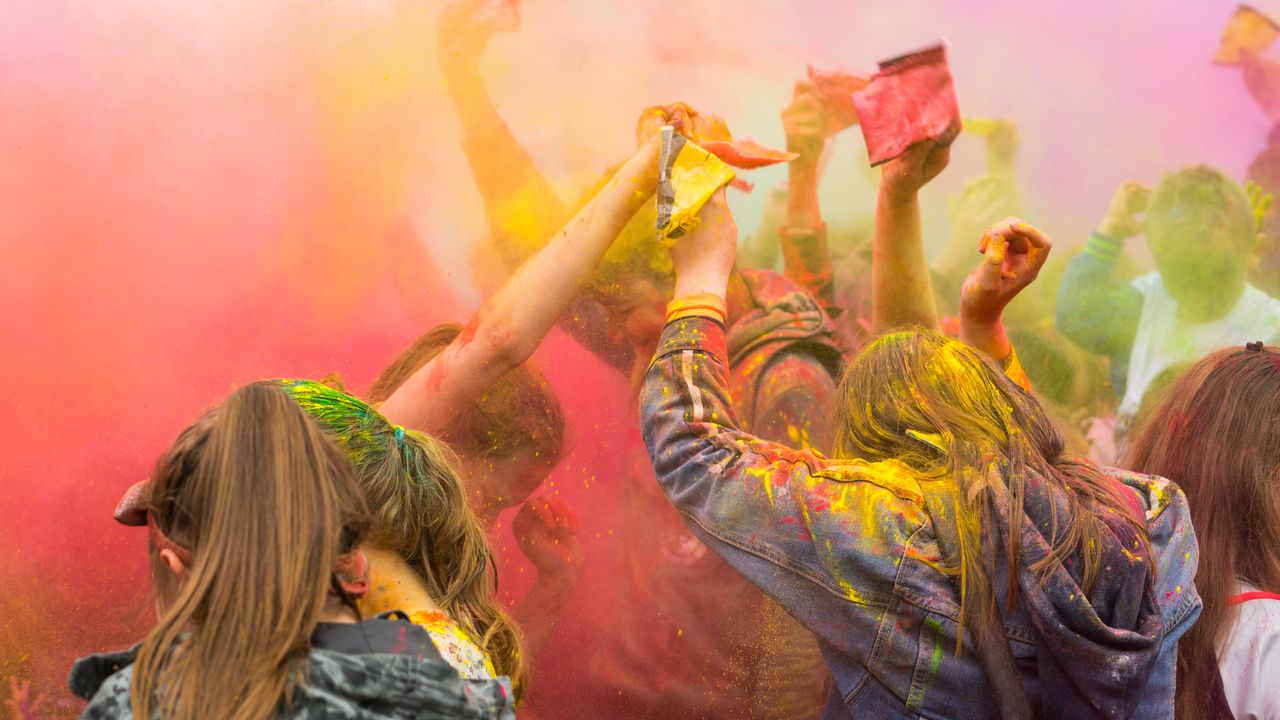 people enjoying a lively festival with colorful powder in the air symb