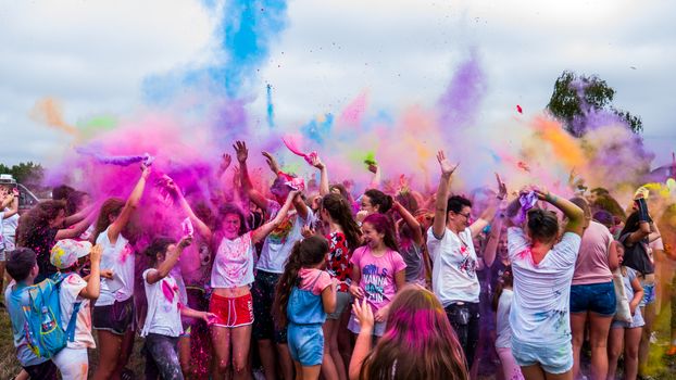 Joyful crowd celebrating with colorful powder outdoors on a festival day.