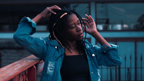 A Woman with Dreadlocks Hair Wearing Denim Jacket while Looking Afar