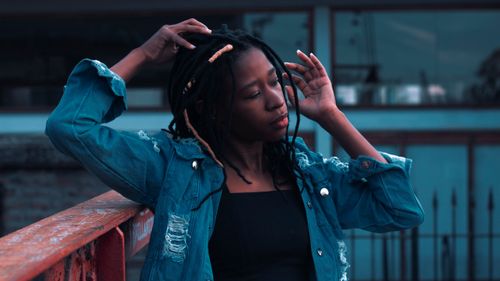 Free Portrait of a young black woman with dreadlocks in a denim jacket, posing outdoors. Stock Photo