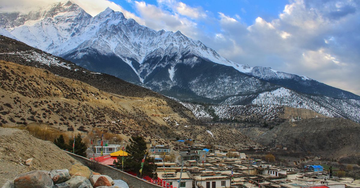 Himalayan village nestled beneath snow peaks in Nepal