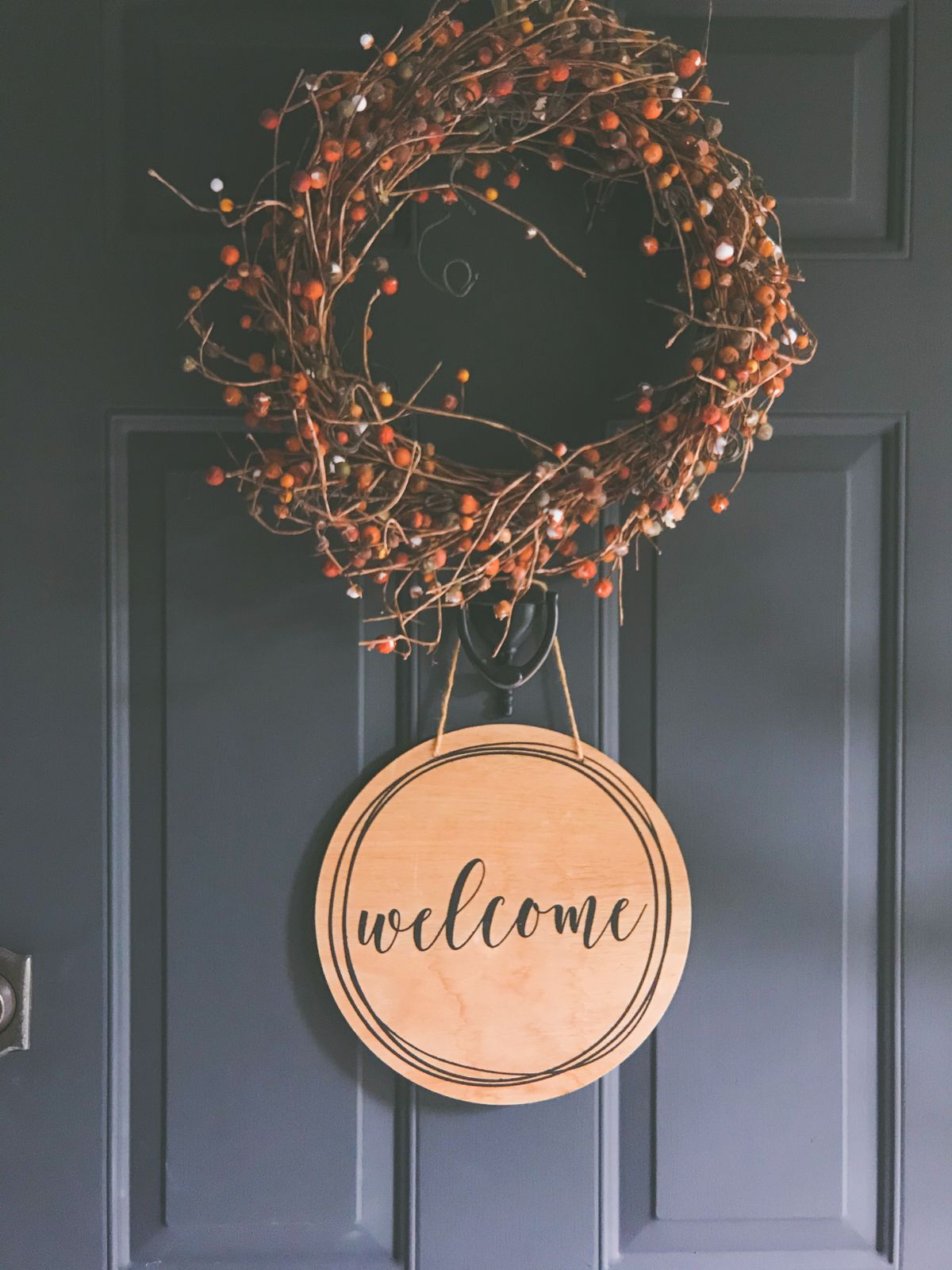 A rustic wreath with a welcome sign on a dark door, creating a warm invitation. Stock Photo.