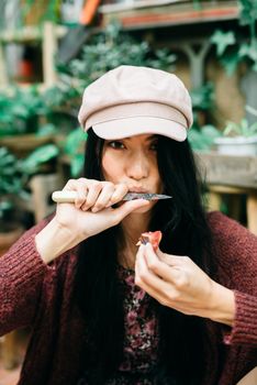 一位亚洲女士在室内戴着帽子和毛衣，享用新鲜水果