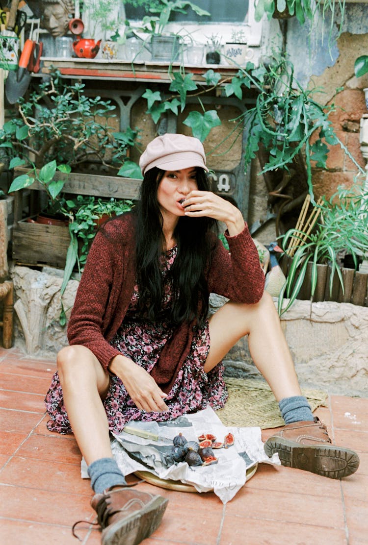 A Woman Sitting On The Floor Eating Figs