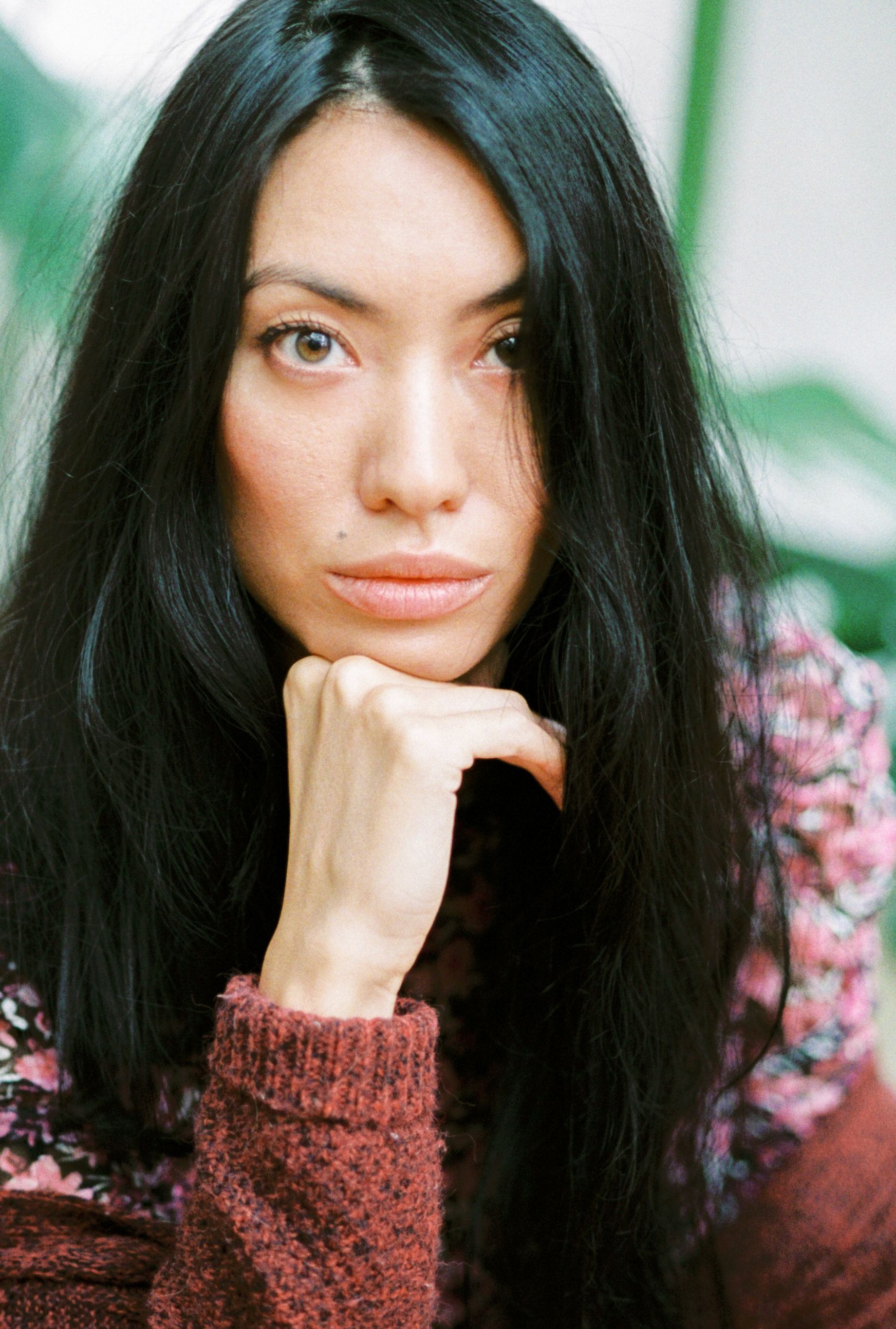 A thoughtful portrait of a woman with long dark hair in a warm, cozy sweater.