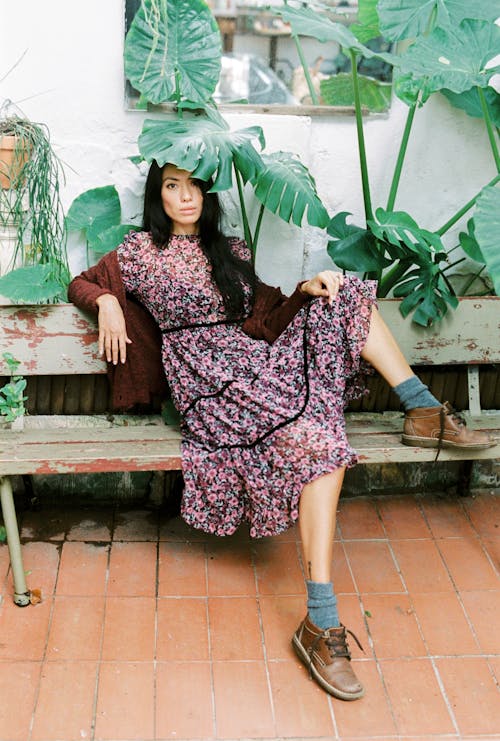 Woman in a Floral Dress Posing on a Wooden Bench