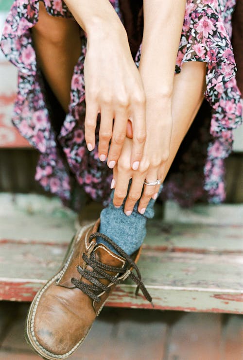 Photograph of a Person's Hands Near Her Brown Boot