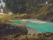 Spectacular scenery of dam near azure water in mountains covered with green grass and trees in daytime