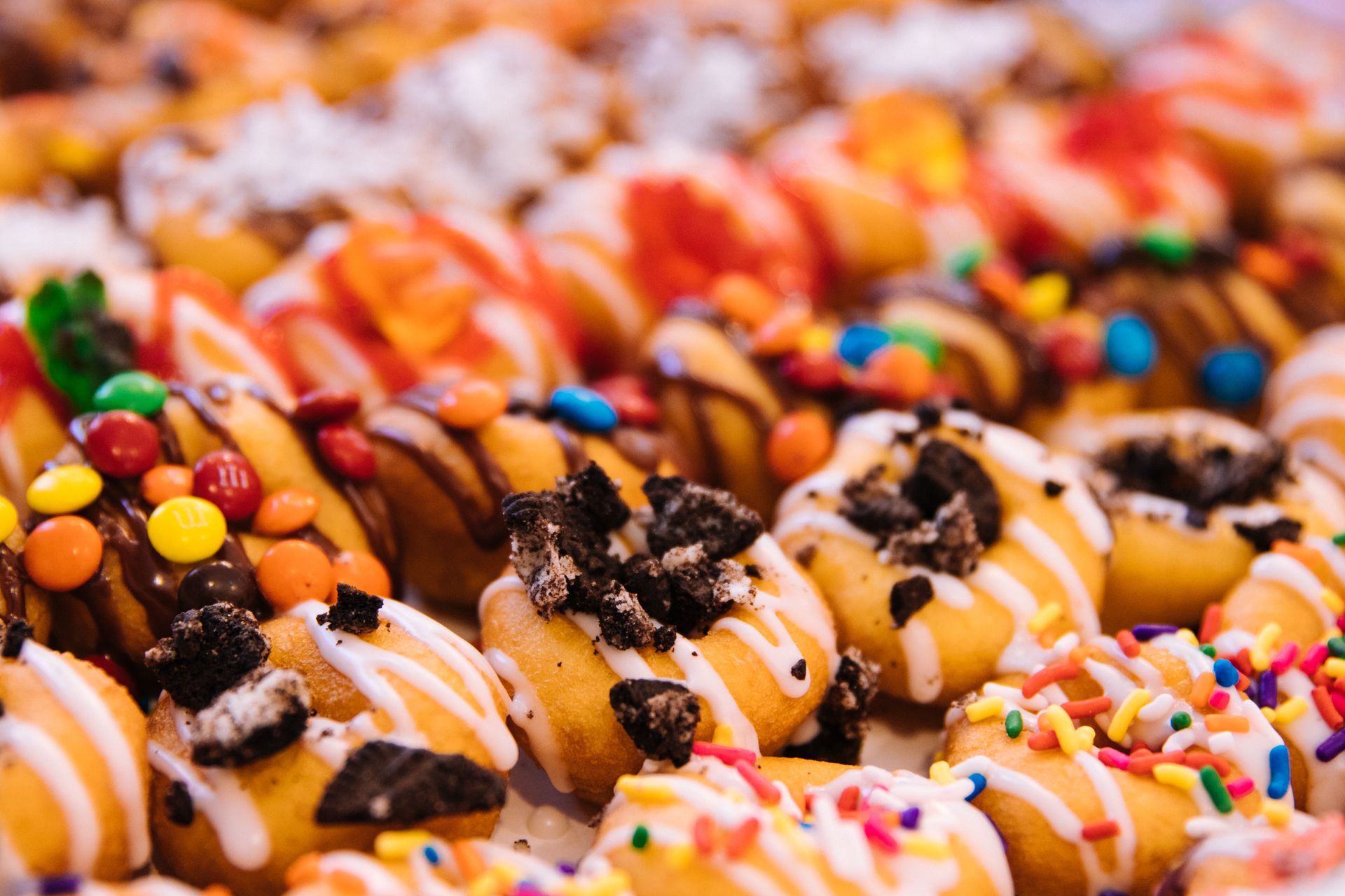 Close-up shot of colorful glazed mini doughnuts with various toppings, perfect for food photography.