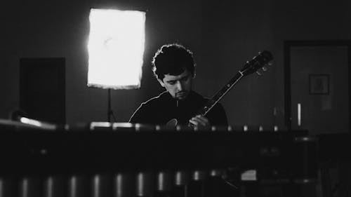 Grayscale Photo of a Man Playing the Guitar