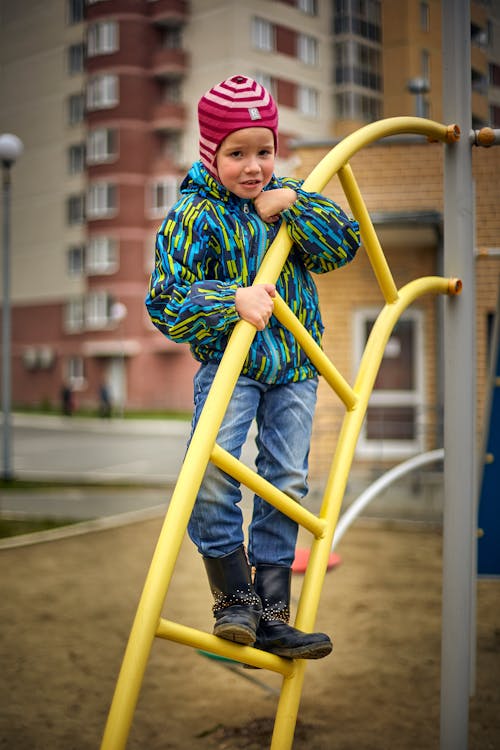 Photo of a Girl in a Blue and Green Jacket Playing at a Playground