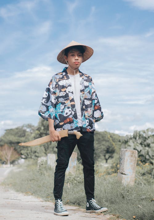 Free Photo of a Boy with an Asian Conical Hat Holding a Sword Stock Photo