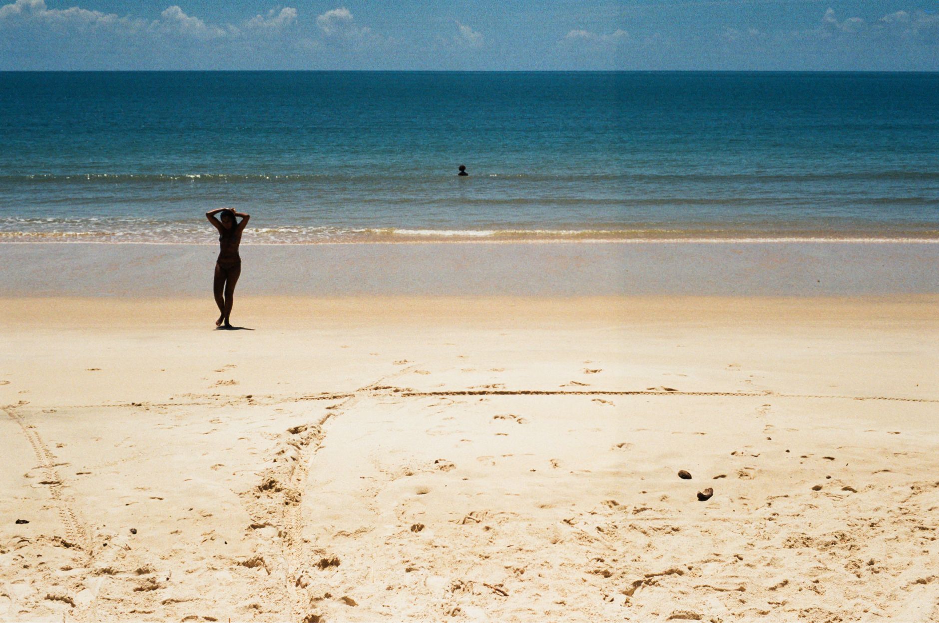 A tranquil scene of an empty beach with a single person enjoying the sun in Bahia, Brazil.
