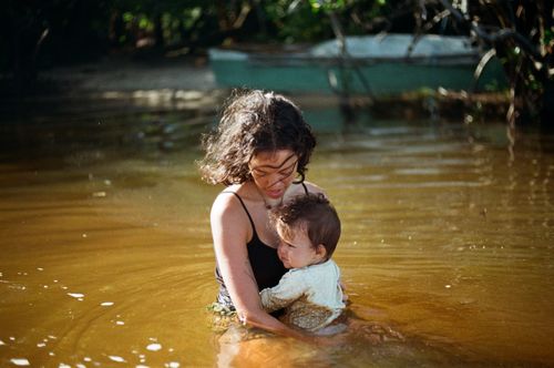 Free A loving mother holds her child in a serene outdoor lake setting, capturing a tender moment. Stock Photo