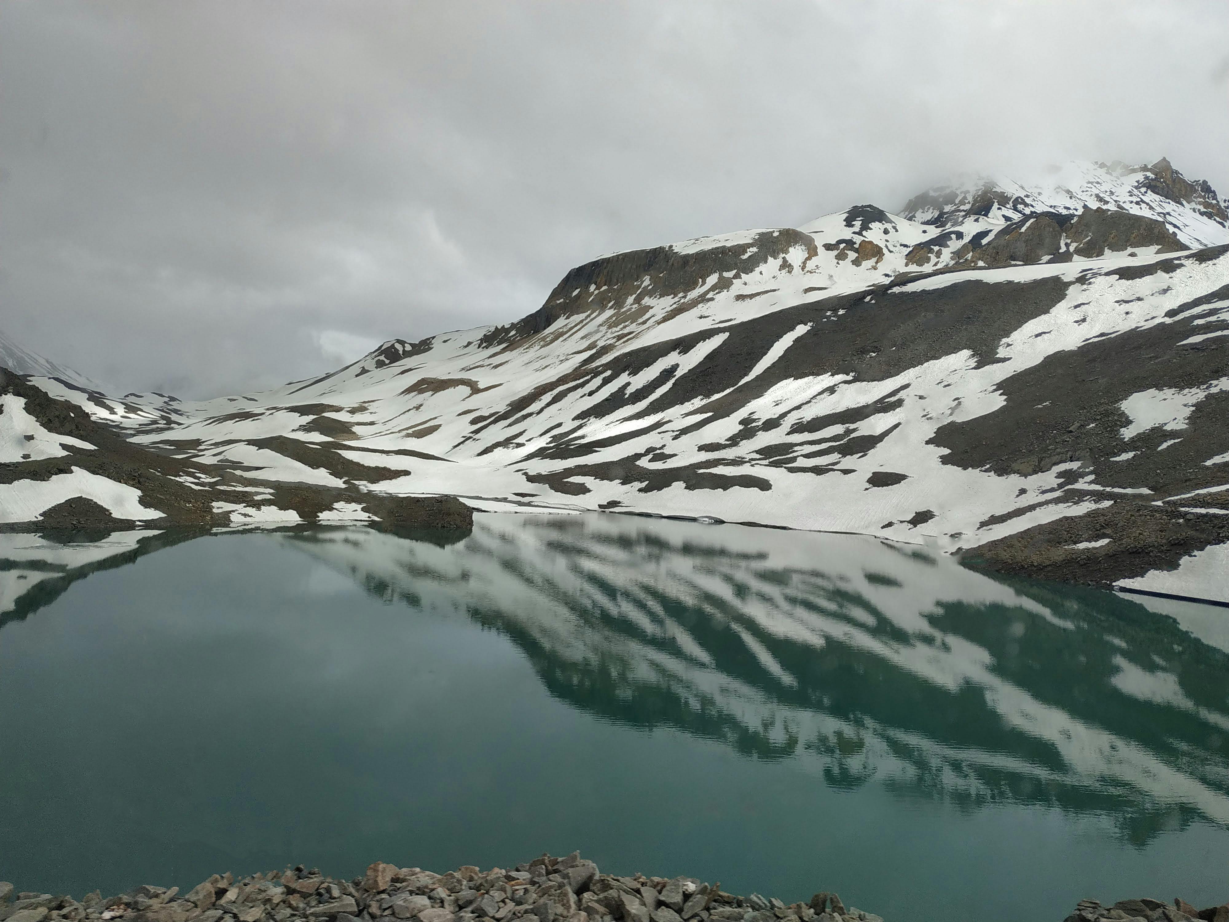 Prescription Goggle Inserts - Tranquil mountain lake with snowy peaks reflected under cloudy skies in Leh, India.