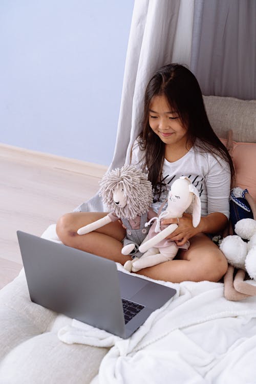 Free Photo of a Girl with Stuffed Toys Looking at a Laptop Stock Photo