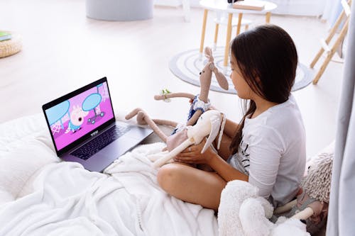 Free Photograph of a Girl Watching on a Laptop with Her Stuffed Toys Stock Photo