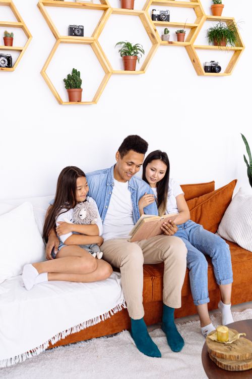 Free A loving family of three reading together on a cozy sofa, enjoying quality time at home. Stock Photo