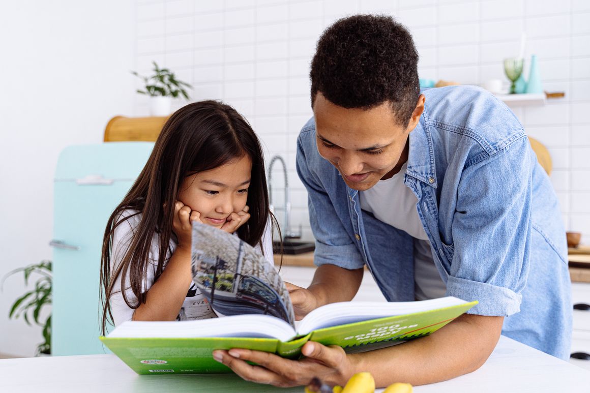 A real father and child reading a book together at home