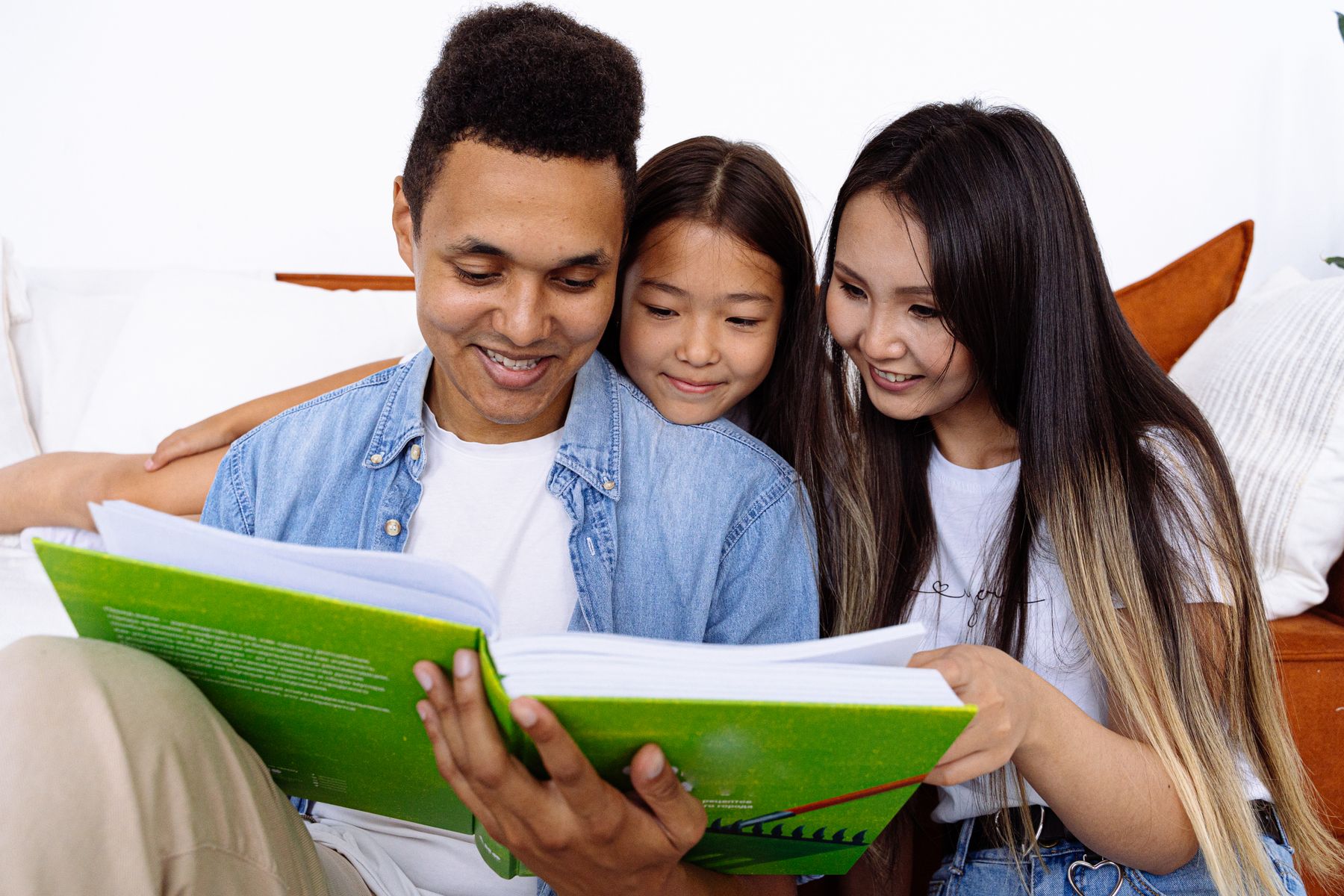 A family reading a picture book together in a bright home to encourage storytelling and shared language