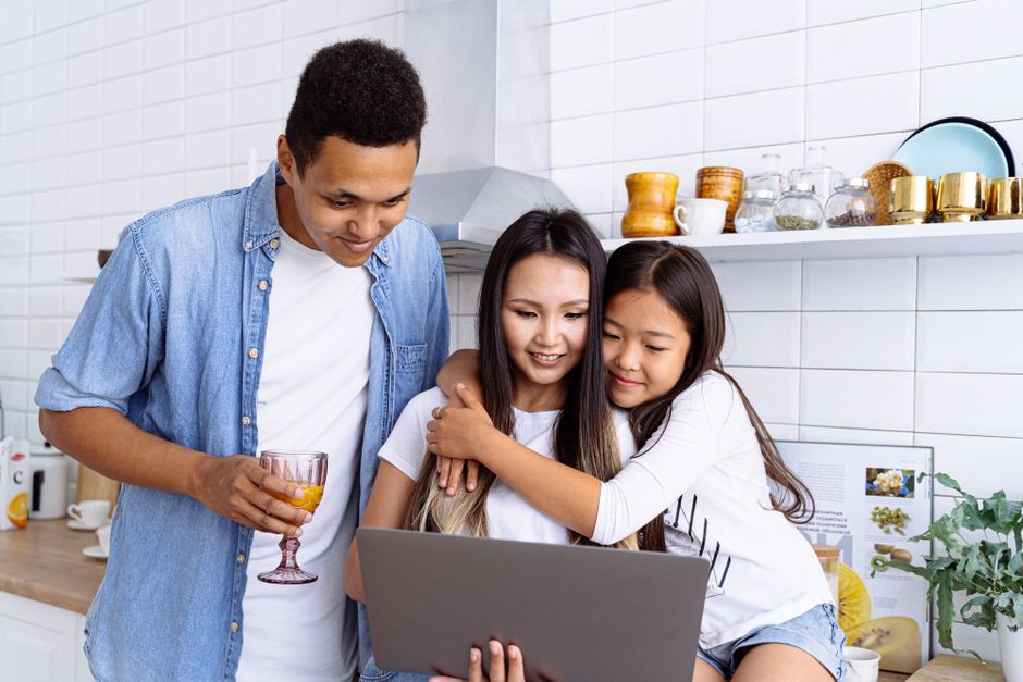 Happy multicultural family enjoying time together with a laptop in a modern kitchen.